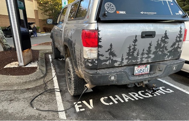 An ICE pickup truck unlawfully parked in an EV charging stall